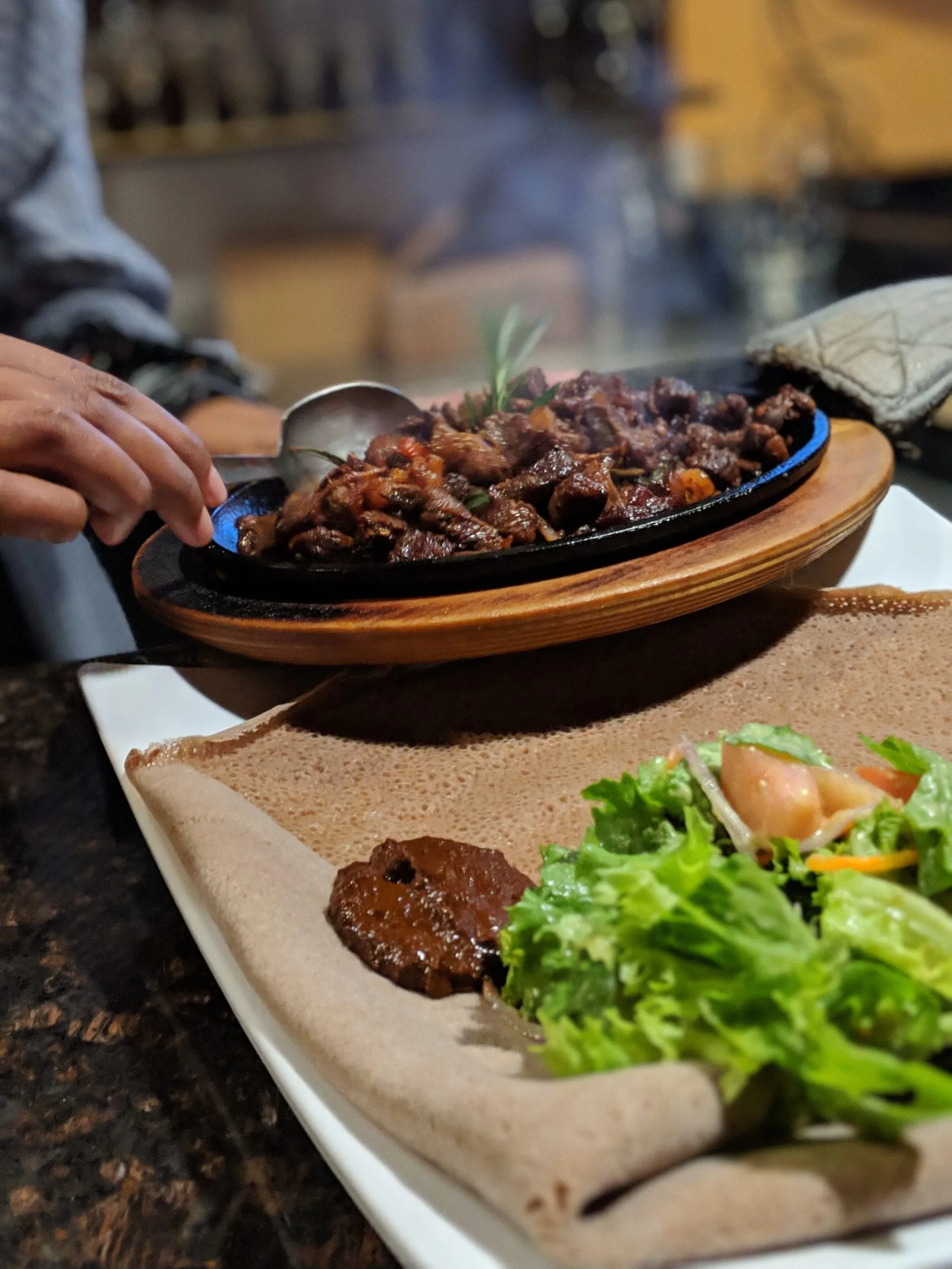 Sizzling tibs served beside injera